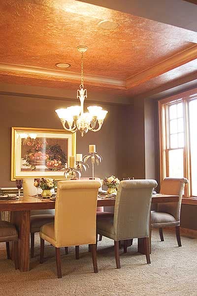 Dining room with coffered ceiling, chandelier, large window, and a table set for a meal.
