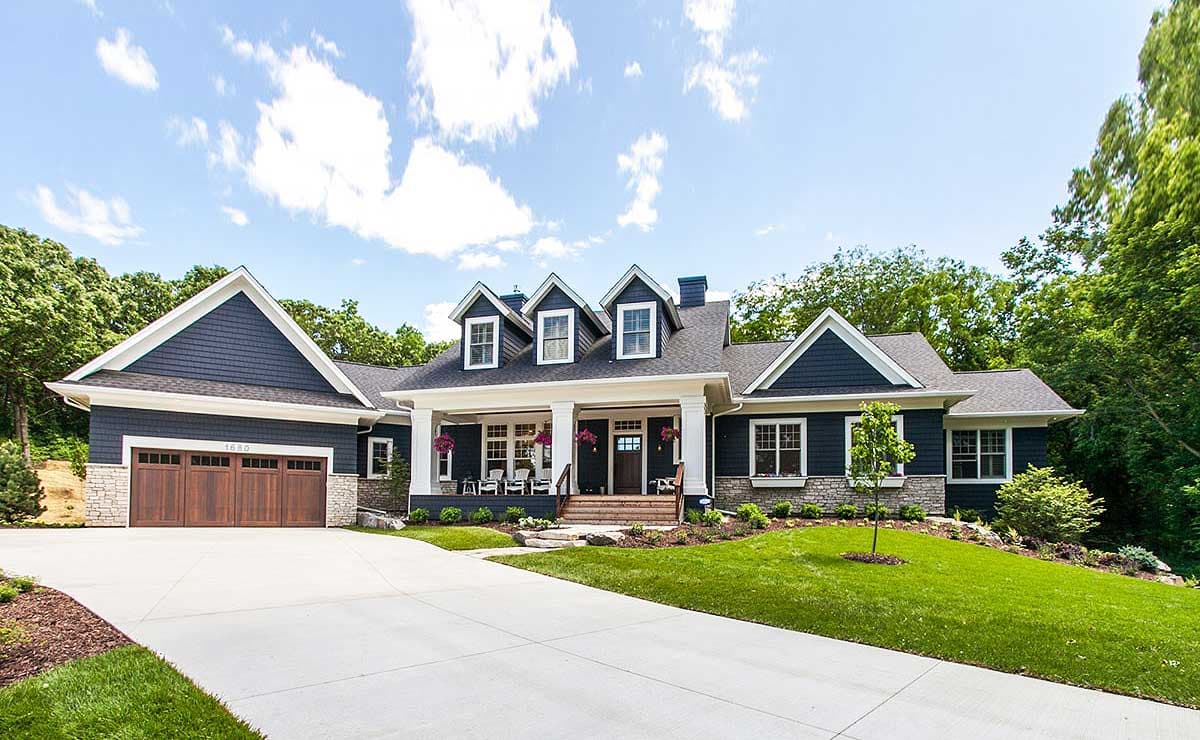 House plan exterior. Two-story Modern Farmhouse style with a front porch, multiple gables, and dormers. Features a side-entry garage.
