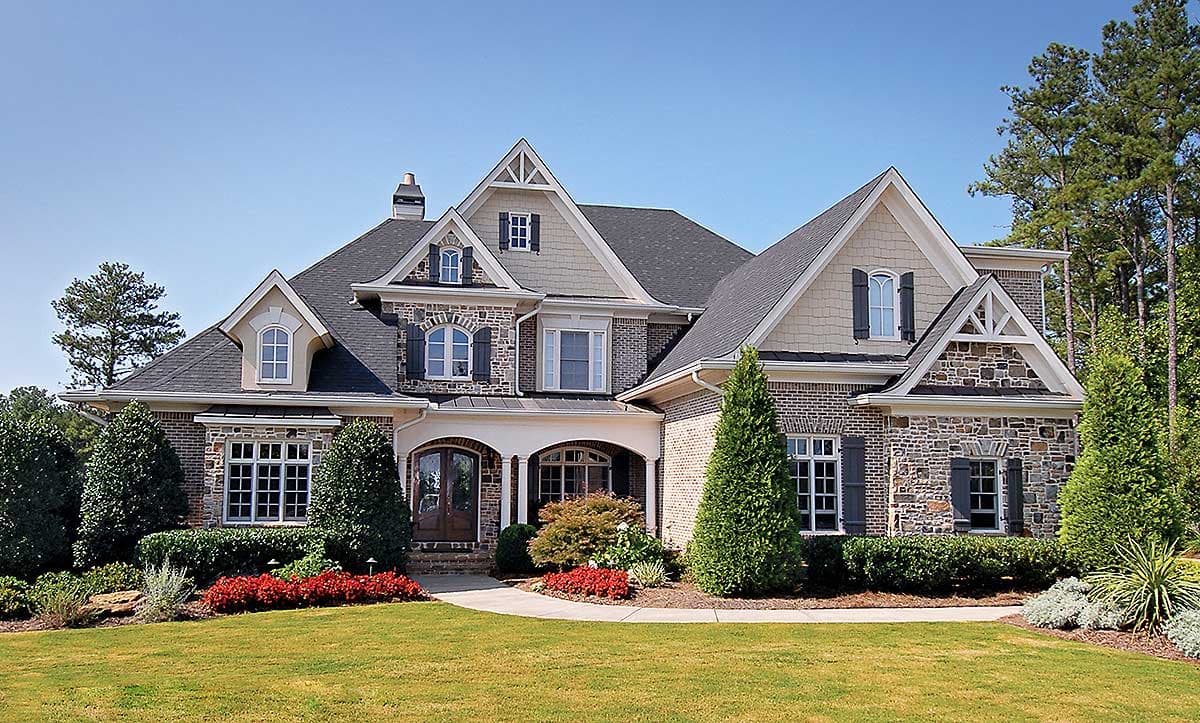 House plan exterior: Two-story home with stone and brick facade, multiple gables, dormers, arched entryway, and varied rooflines.