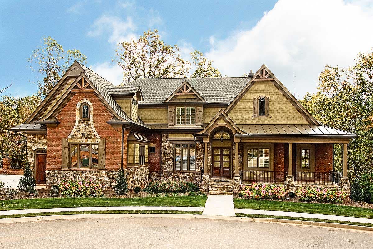House plan exterior: Two-story home with brick and stone facade, prominent gables, arched entry, and wraparound porch.