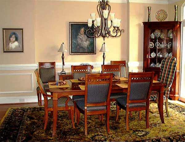 Dining room with wooden table and chairs, chandelier, china cabinet, and patterned rug.