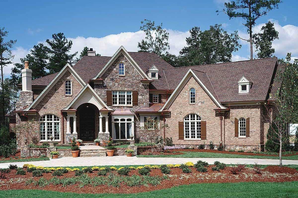 House plan exterior with stone and brick facade, multiple gables, arched windows, and covered entryway.