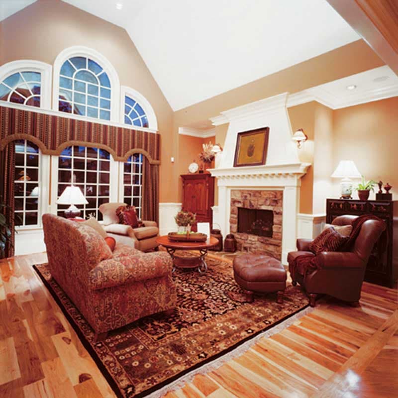Great room interior with vaulted ceiling, stone fireplace, and arched multi-pane windows.