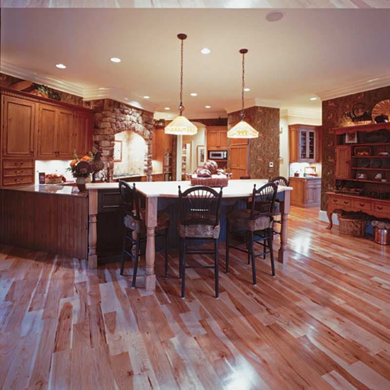 Kitchen with large island, stone range hood, wood cabinetry, and pendant lighting.