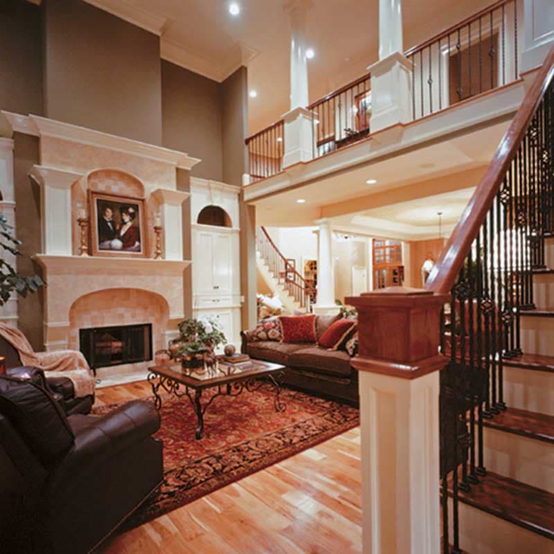 Interior rendering of a great room with a fireplace, grand staircase, and a second-story balcony overlook.