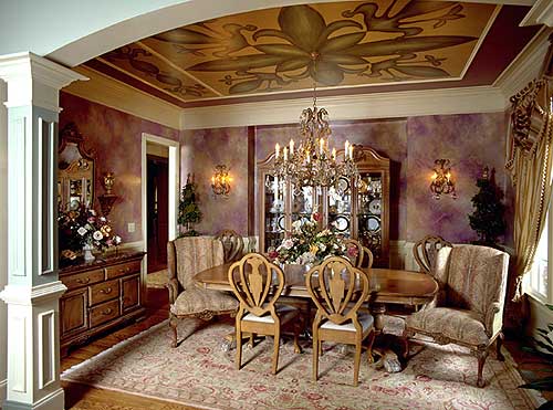 Dining room with ornate chandelier, painted ceiling, buffet, and upholstered chairs around a wooden table.