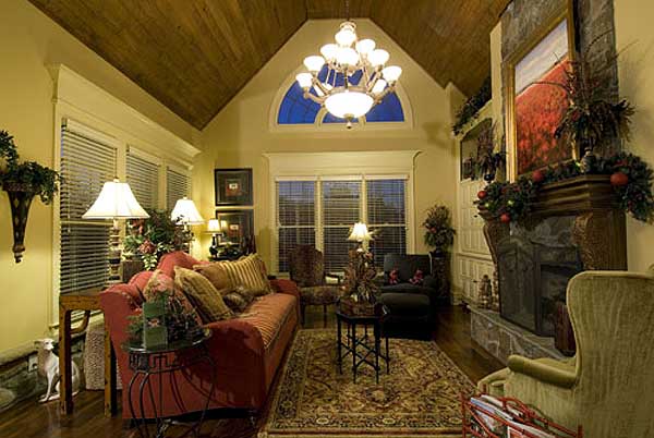 Living room with vaulted wood-paneled ceiling, large stone fireplace, and arched window.