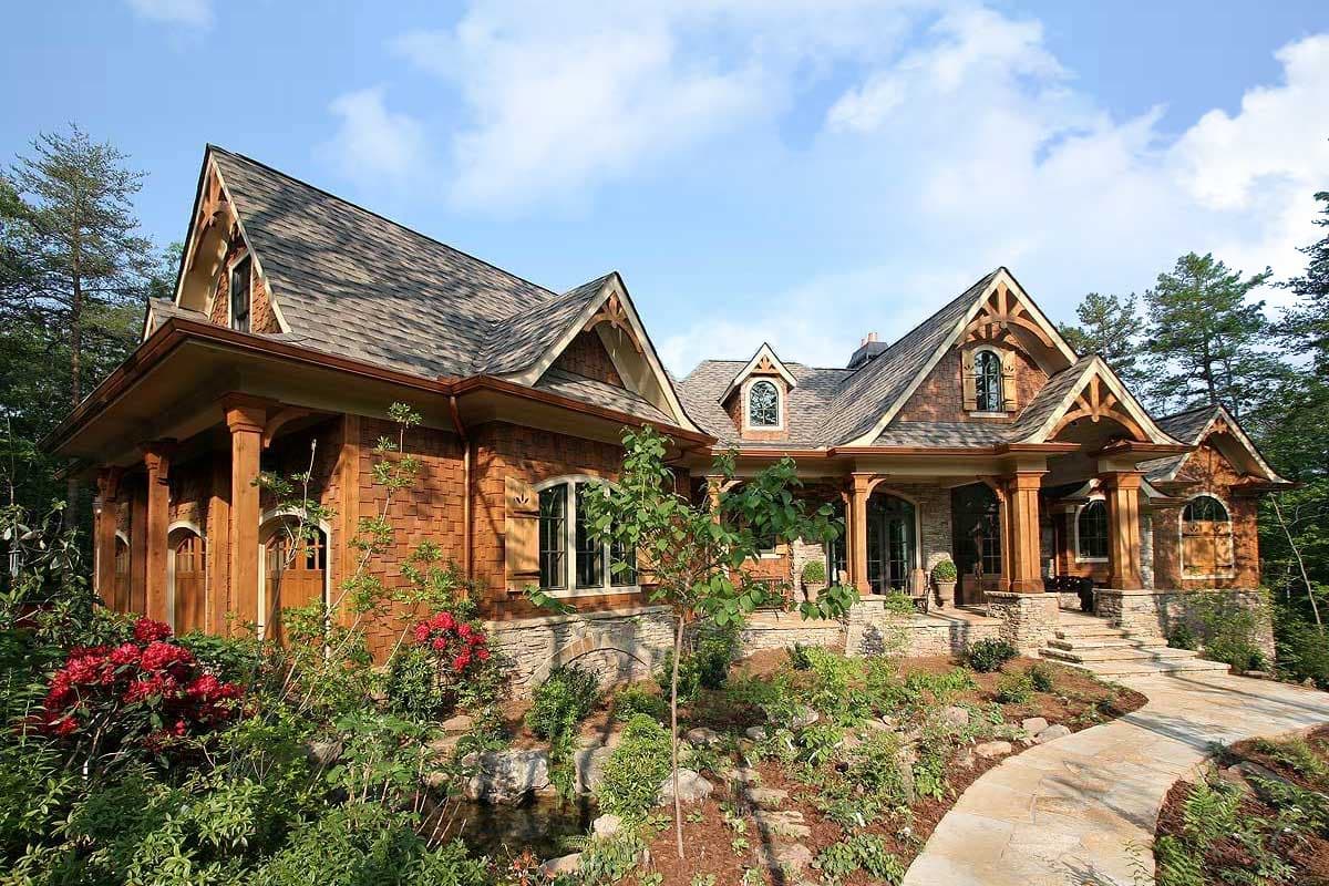 House plan exterior with stone foundation, wood siding, multiple gables, and covered porches with timber supports.