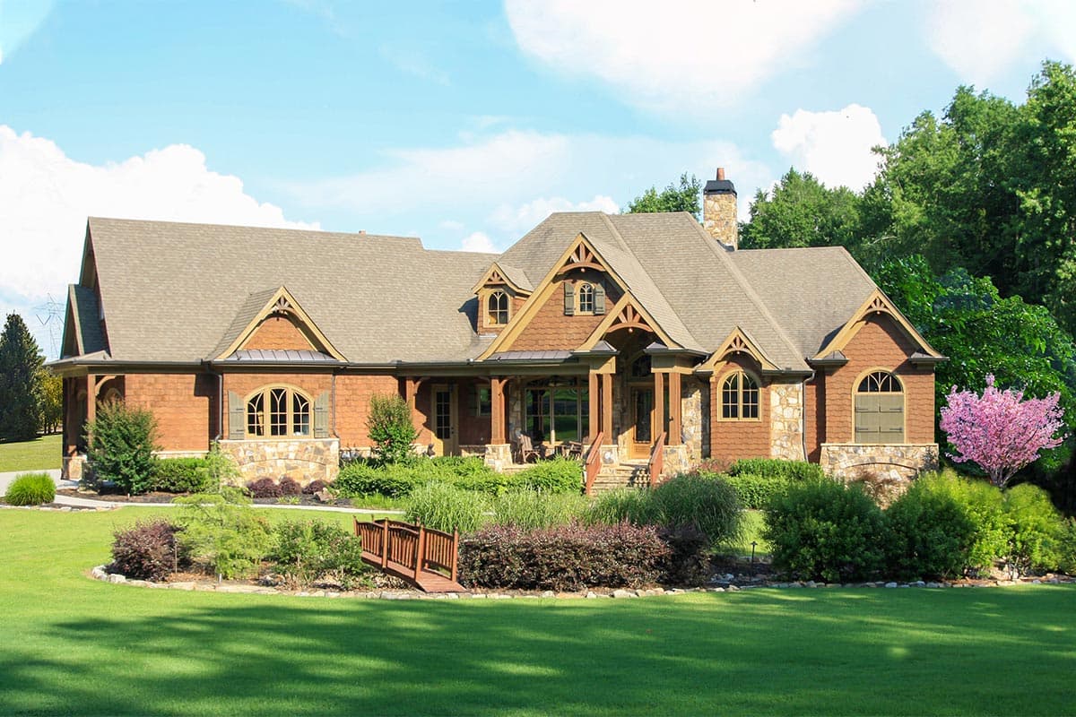 Craftsman style house plan exterior with stone and wood siding, a covered porch, dormers, and multiple gables.