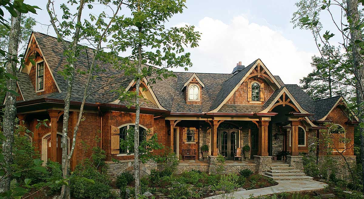 Craftsman style house exterior with stone and wood siding, multiple gables, dormers, and a covered porch.