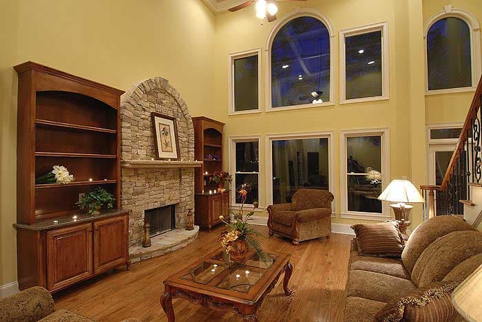 Living room with stone fireplace, built-in bookshelves, and tall arched windows.