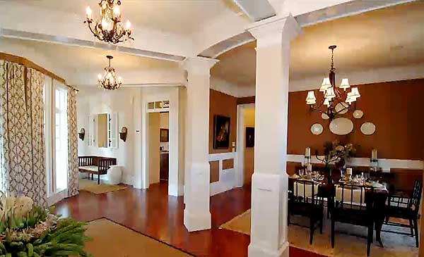Interior view of a dining room with a table set for dinner and an adjacent entryway with a bench.