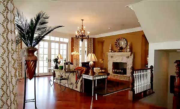 Interior view of a living room with a stone fireplace, a large island, and French doors.