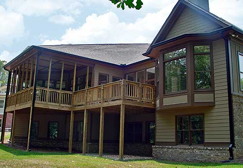 House plan exterior view showing a two-story home with a screened porch, wooden deck, and bay window.
