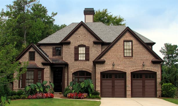 House plan exterior: Brick two-story home with double garage, arched doorways, bay window, and gabled roof.