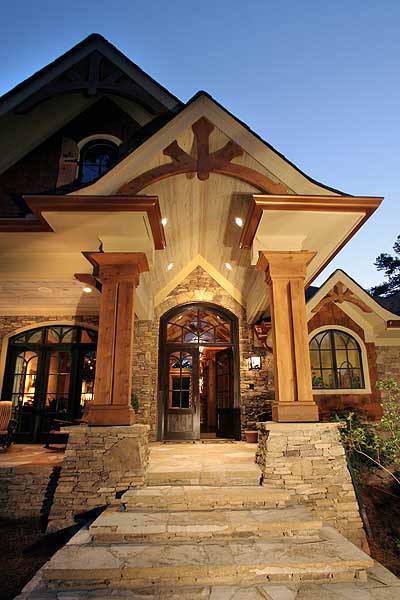 Craftsman house plan exterior: Stone and wood facade with arched entry, large timber posts, and prominent gables.