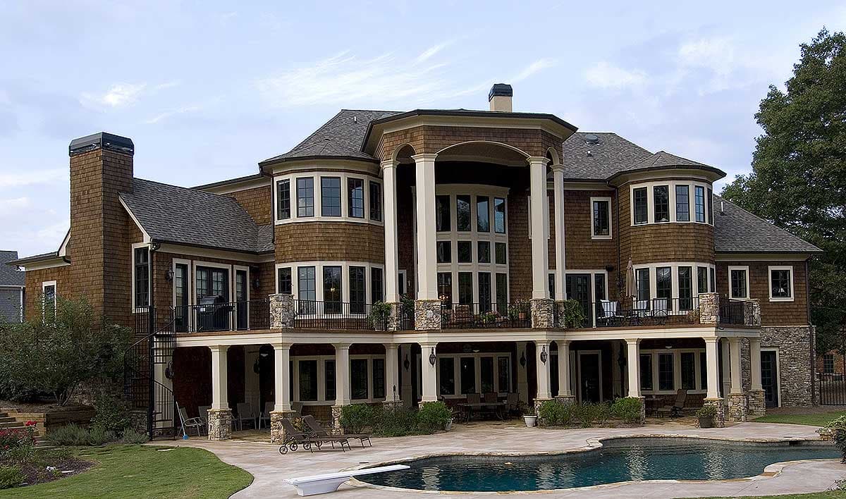 House plan exterior: large multi-story home with shingle siding, gables, multiple bay windows, and a covered porch with columns.