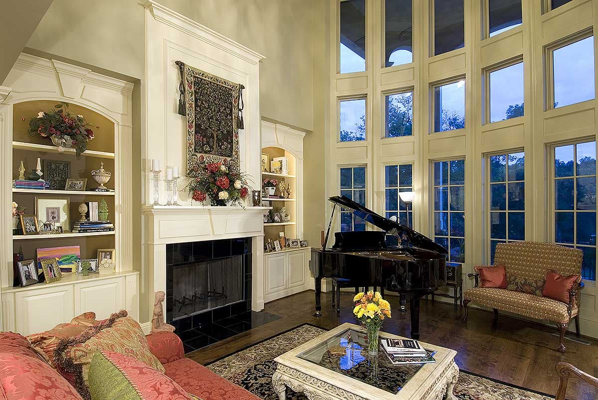 Great room with fireplace, built-in bookshelves, grand piano, and floor-to-ceiling windows.