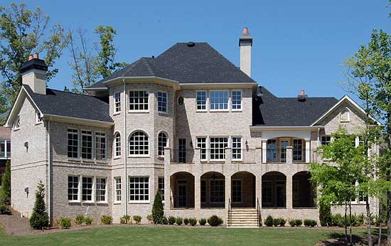 House plan exterior view of a two-story brick home with arched loggias, multiple gables, and prominent chimneys.