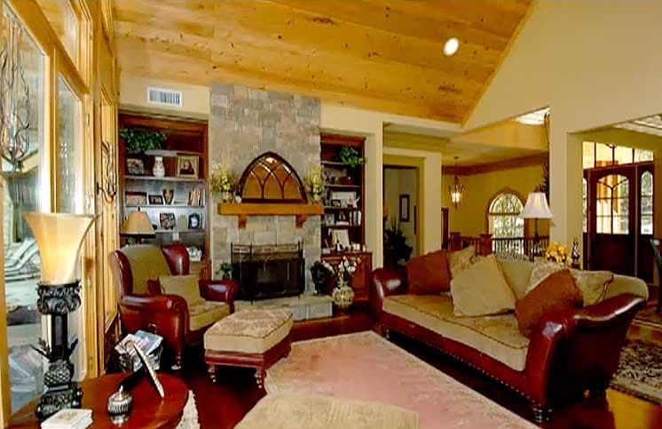 Living room with stone fireplace, built-in bookshelves, and vaulted wood-paneled ceiling.