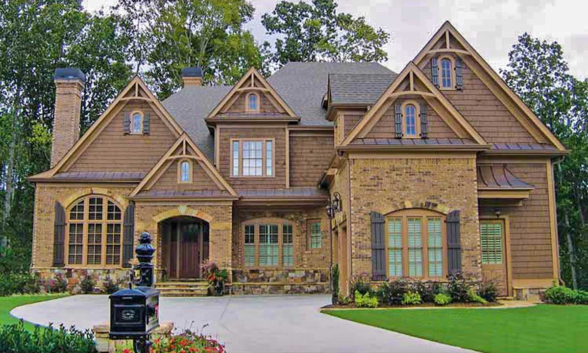 House plan exterior: Traditional style, two stories, brick and wood siding, prominent gables, arched entry, and dormers.