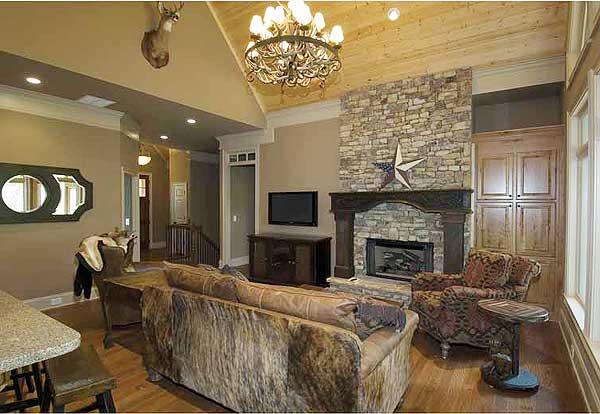 Interior view of a living room with vaulted wood ceiling, stone fireplace, built-in cabinets, and furniture.