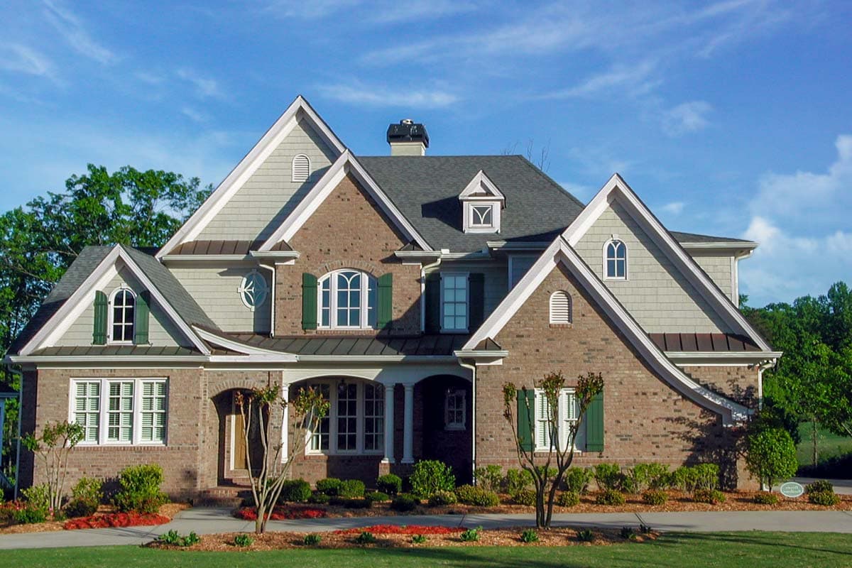 House plan exterior with brick facade, multiple gables, arched windows, dormers, and covered entry.