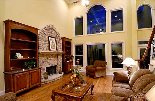 Interior rendering: Living room with stone fireplace, built-in bookcases, and large arched windows.