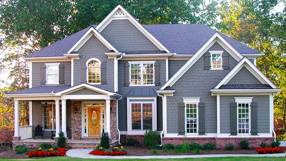 House plan exterior of a two-story home with a wrap-around porch, gables, dormers, and stone accents.