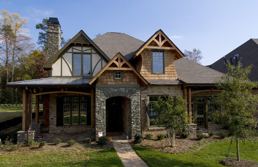 Craftsman house plan exterior with stone archway, gabled dormers, timber posts, and metal roof.