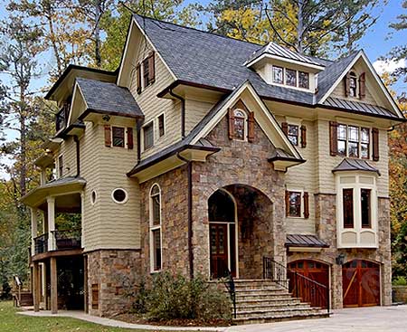 Traditional house plan exterior with stone accents, multiple gables, a wraparound porch, and a three-car garage.