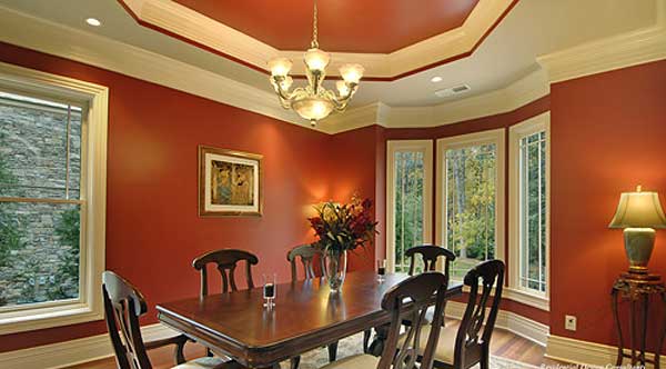 Dining room with a large wooden table, chairs, multi-pane windows, and a tiered ceiling with chandelier.