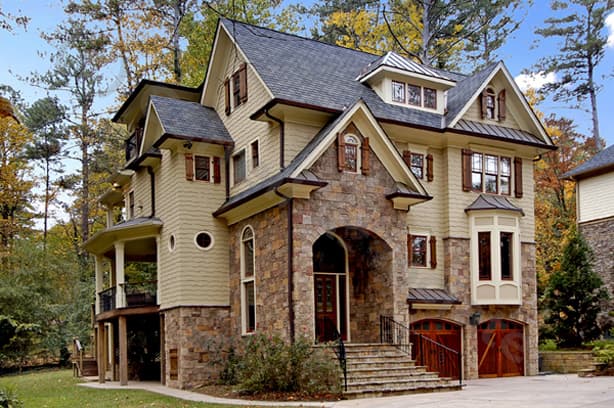 House plan exterior: Traditional style, three-story home with stone base, arched entry, bay window, and attached two-car garage.