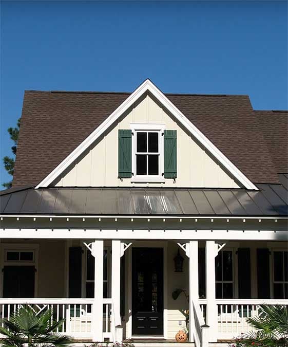 House plan exterior featuring a gable dormer with green shutters, a covered front porch with white railings and columns, and a metal roof.