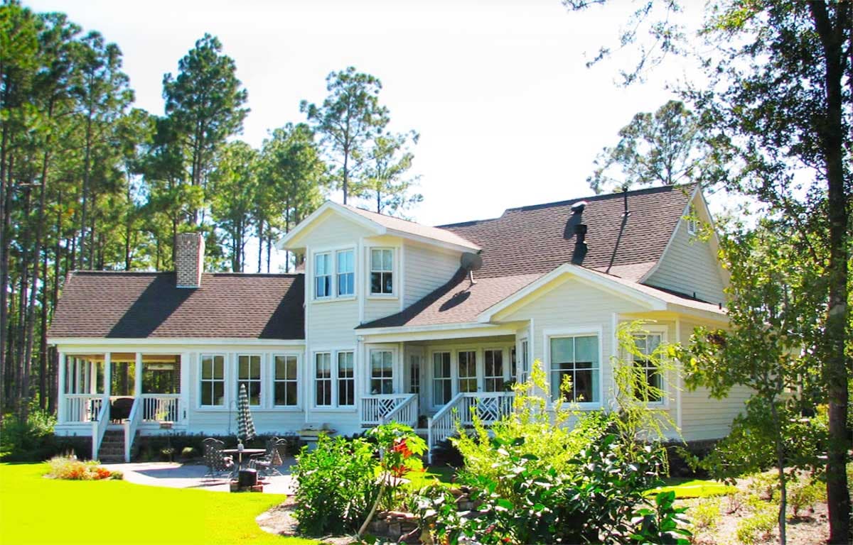 House plan exterior of a two-story home with gables, a screened porch, and a prominent brick chimney.