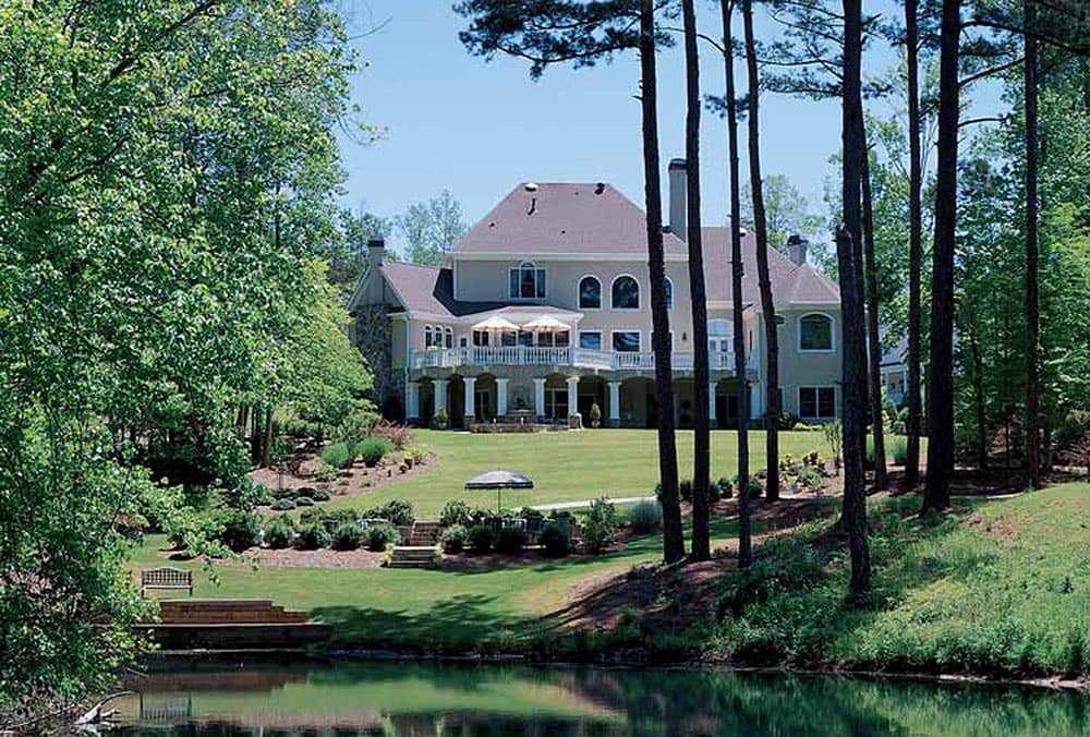 House plan exterior, two-story home with stone accents, multiple gables, and a wraparound porch with columns.