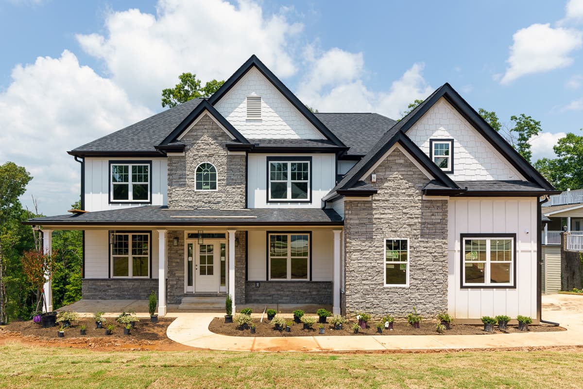 House plan exterior with stone accents, covered porch, and gabled roof. Features include a two-story design and decorative trim around windows.
