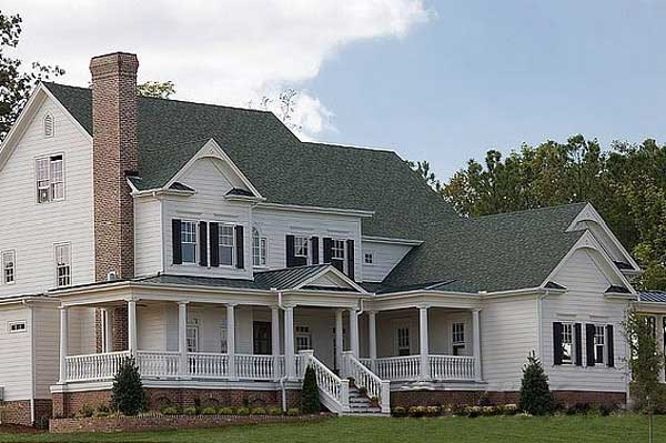 House plan exterior: two-story white home with wraparound porch, gabled dormers, and a prominent brick chimney.