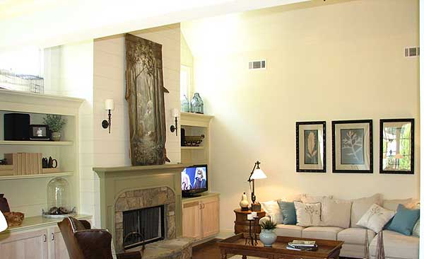 Great room with stone fireplace, built-in shelving, vaulted ceiling, and sectional sofa.