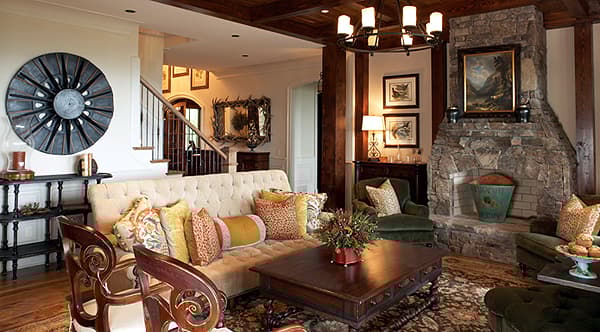 Great room with stone fireplace, tufted sofa, and wood-beamed ceiling.