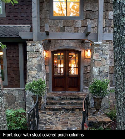House plan exterior: Double wood doors with arched transom, stone-clad porch columns, stone pathway, and shake siding.