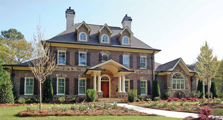 House plan exterior: Brick two-story with prominent gabled dormers, arched windows, and a covered portico with columns.