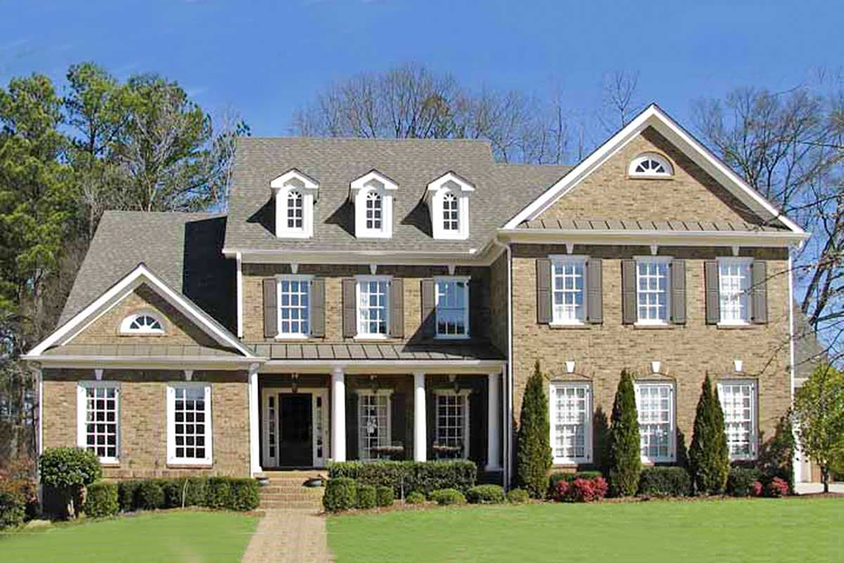 Two-story house plan exterior featuring a brick facade, gabled roof, dormers, and a covered porch with white columns.