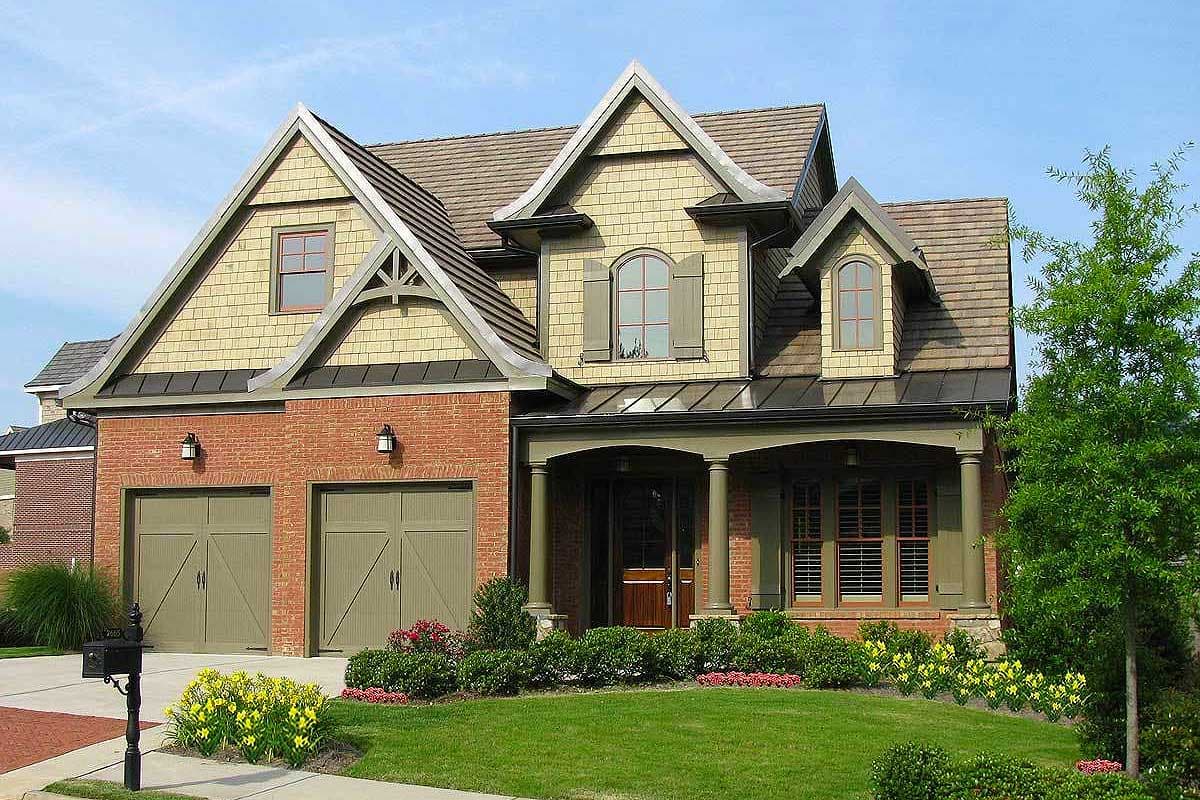 House plan exterior: Brick and shingle siding, gabled dormers, covered front porch with columns, and a side-entry two-car garage.