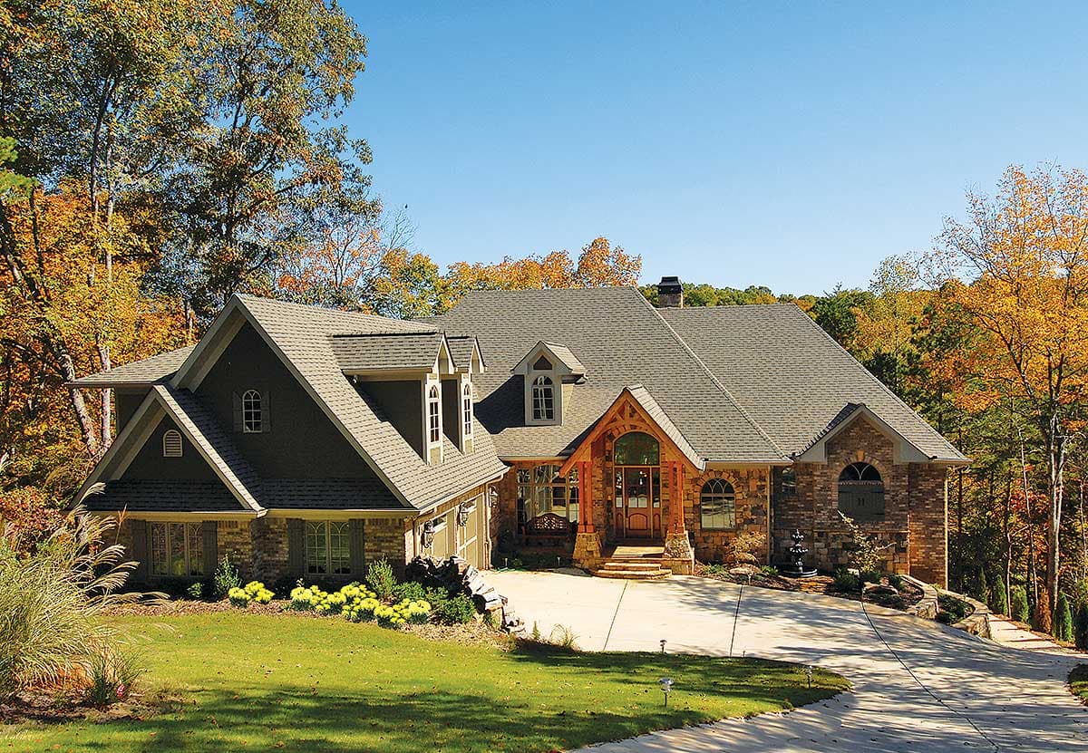 House plan exterior: Two-story home with multi-level rooflines, arched dormers, stone facade, and covered entry.
