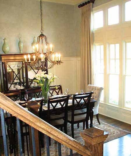 Dining room with wood dining table, ornate chandelier, china cabinet, and large multi-paned windows.