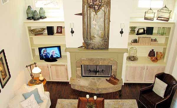 Living room with built-in shelving flanking stone fireplace, television, and seating area.