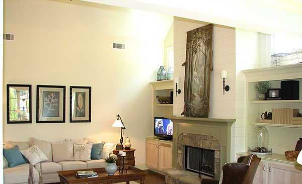 Living room with stone fireplace, vaulted ceiling, built-in shelving, and framed art.