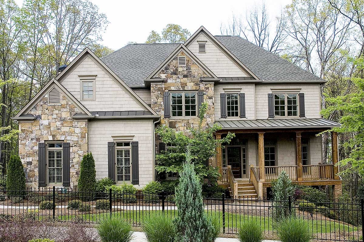 House plan exterior: Two-story home with stone and shingle siding, prominent gables, and a covered front porch.