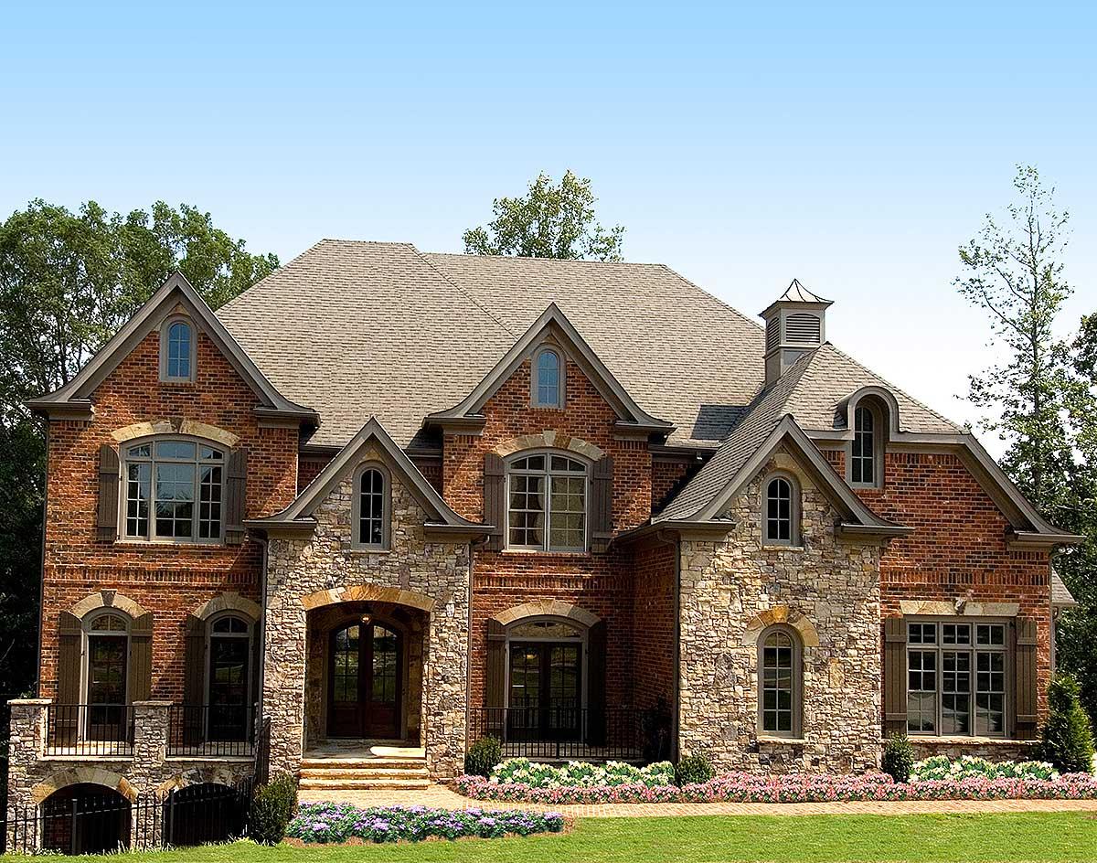 House plan exterior with brick and stone facade, arched entryway, multiple gables, and dormer windows.